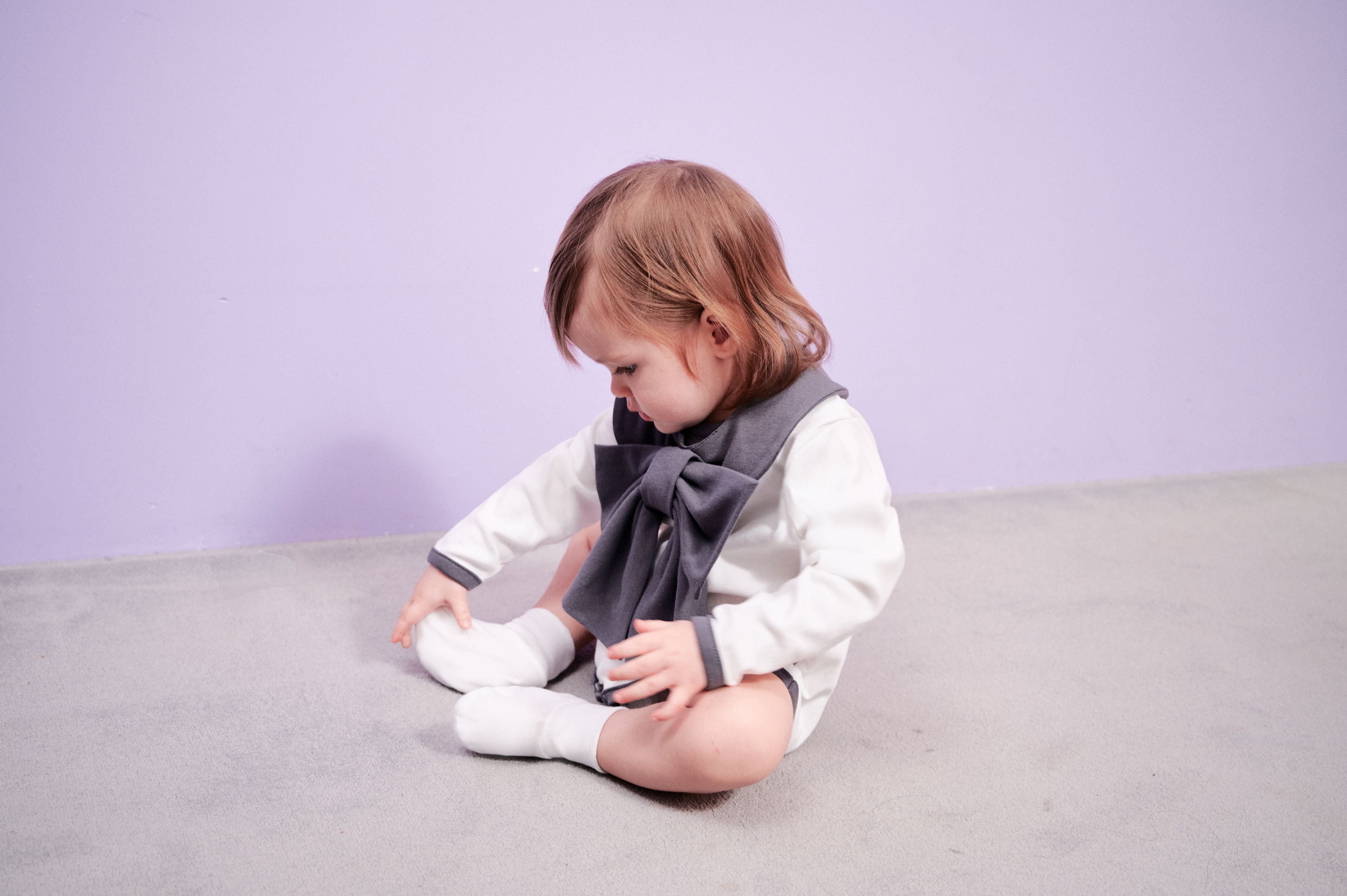 Dress Up Bodysuit (Off White): Minimalistic design with contrasting lines and charming pocket details. Paired with a ribbon scarf bib for a formal look.